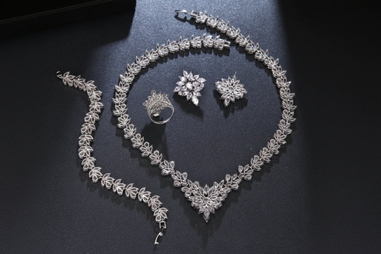 Silver jewelry set including necklace, bracelet, ring, and earrings on a dark surface