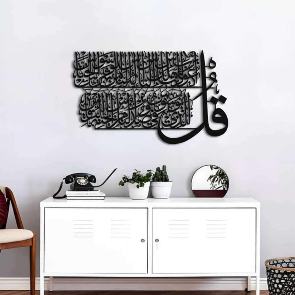 Decorative wall art with Arabic calligraphy on a white wall above a white cabinet.