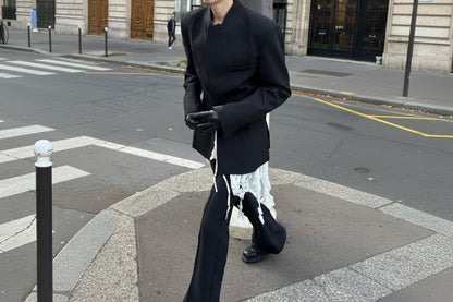 Person wearing a black coat and gloves on a city street.