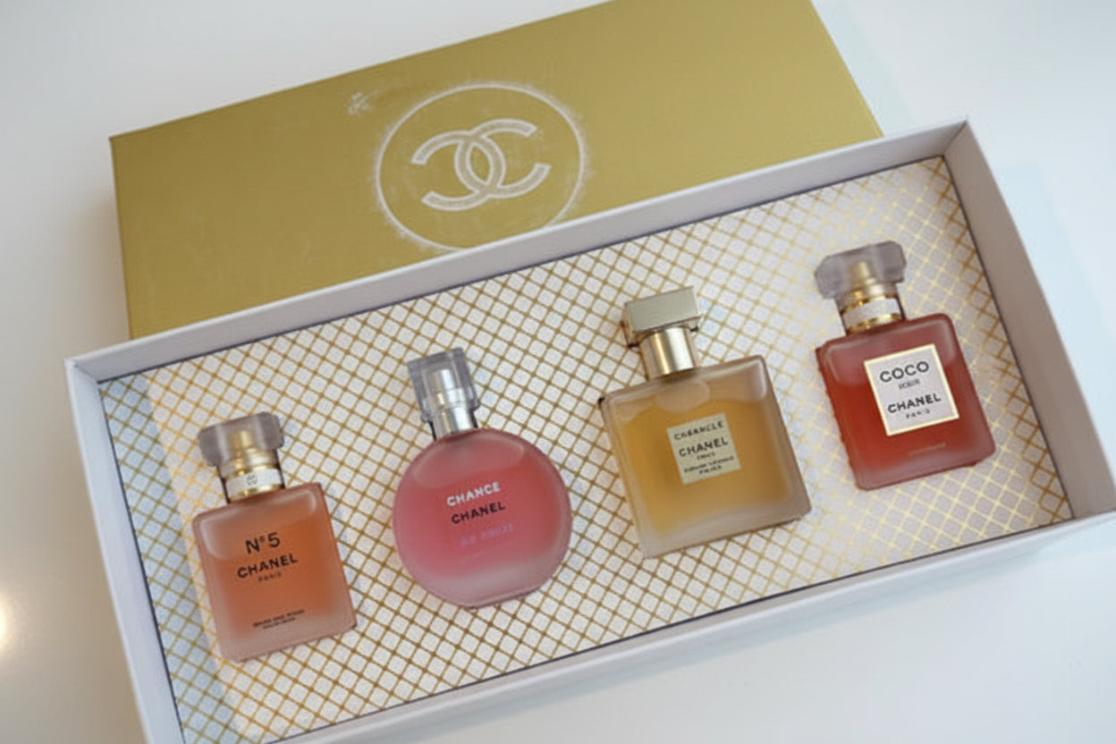 Four Chanel perfume bottles in a decorative box with a gold lid featuring the Chanel logo.