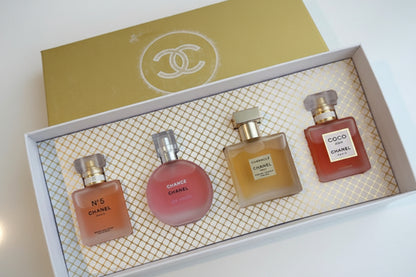 Four Chanel perfume bottles in a decorative box with a gold lid featuring the Chanel logo.
