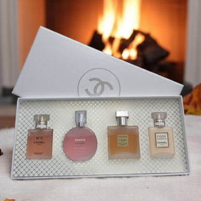 Set of four perfume bottles in a decorative box with a fireplace in the background