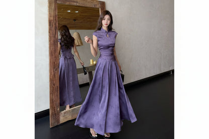Woman in a long purple dress standing in front of a mirror.