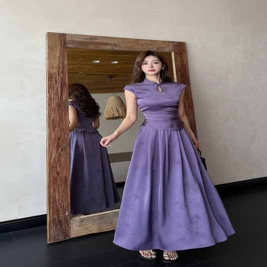 Woman in a long purple dress standing in front of a mirror.