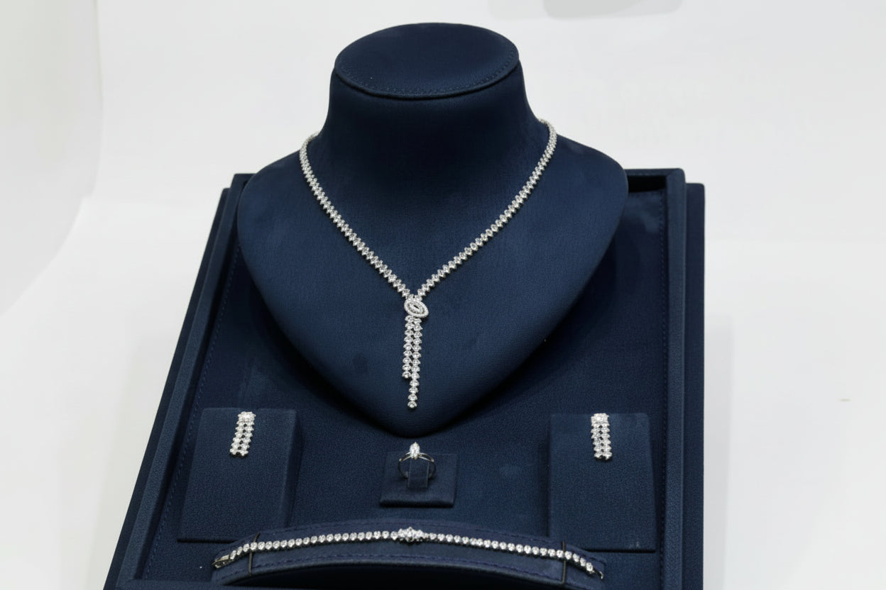 Silver necklace on a dark blue velvet stand with a white background