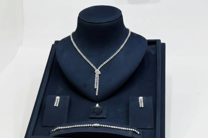 Silver necklace on a dark blue velvet stand with a white background