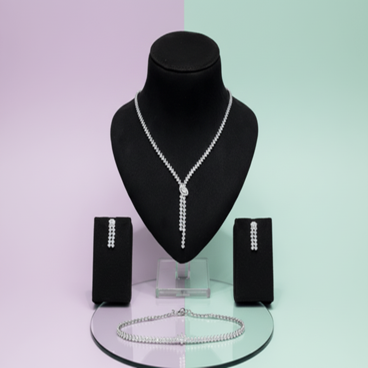 Jewelry set with necklace, earrings, and bracelet on a mannequin bust against a two-tone background.