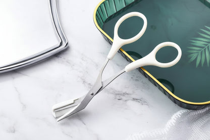 Pair of white-handled scissors on a marble surface with a green cutting board in the background.
