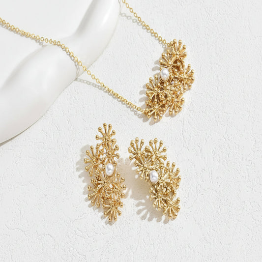 Gold necklace and earrings with pearl accents on a white background