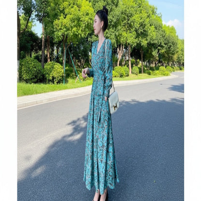 Woman in a blue floral dress standing on a road with greenery in the background