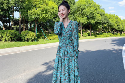 Woman in a green dress standing on a road with trees in the background