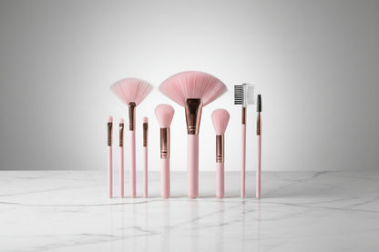 Set of pink and rose gold makeup brushes on a light gray background