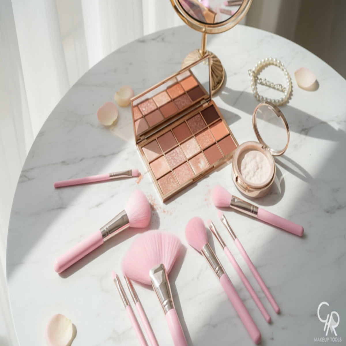 Makeup set with pink brushes and a compact mirror on a marble surface