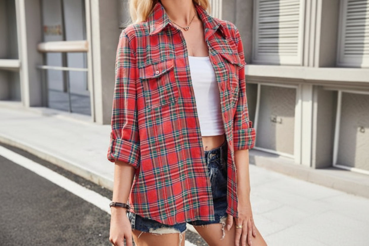 Person wearing a red plaid shirt over a white top and denim shorts outdoors.