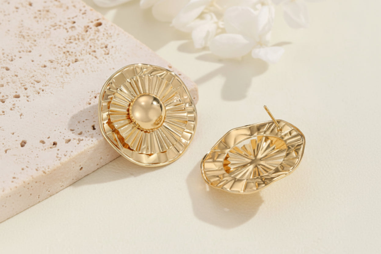 Gold earrings on a light background with flowers