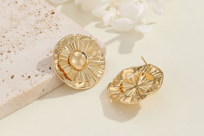 Gold earrings on a light background with flowers