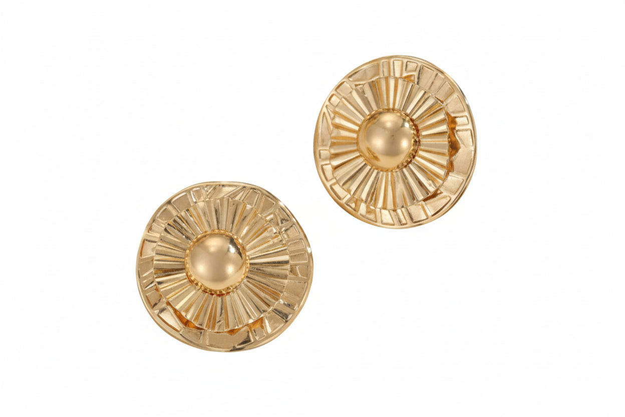 Pair of gold round earrings with sunburst design on a white background