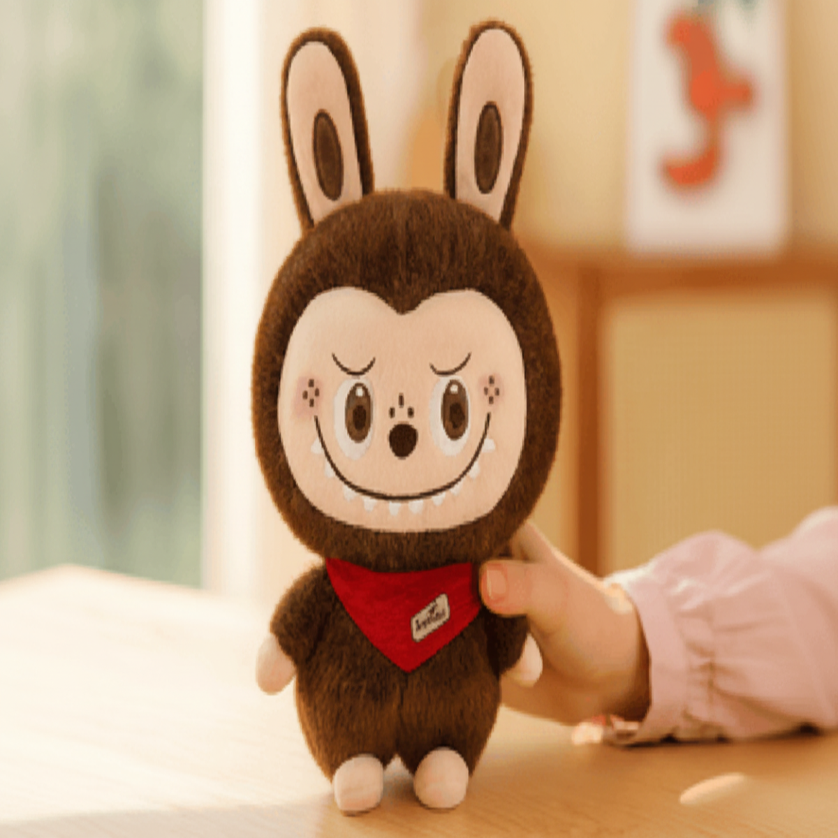 Plush toy with a cartoonish design held by a hand on a light surface.