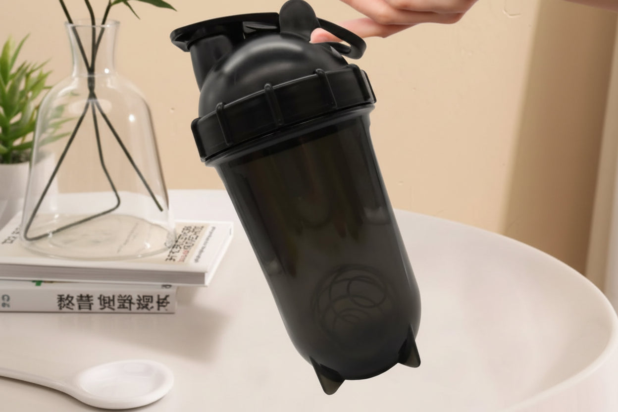 Black shaker bottle held by a hand on a beige background