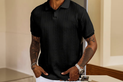 Person wearing a black textured polo shirt with tattoos on arms.