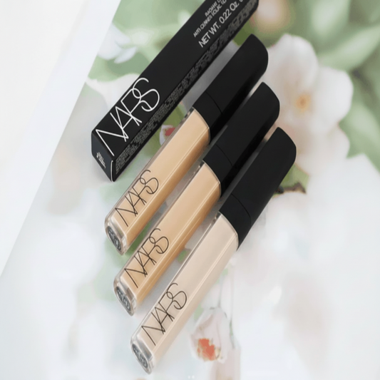 Three NARS concealer bottles with a box on a floral background