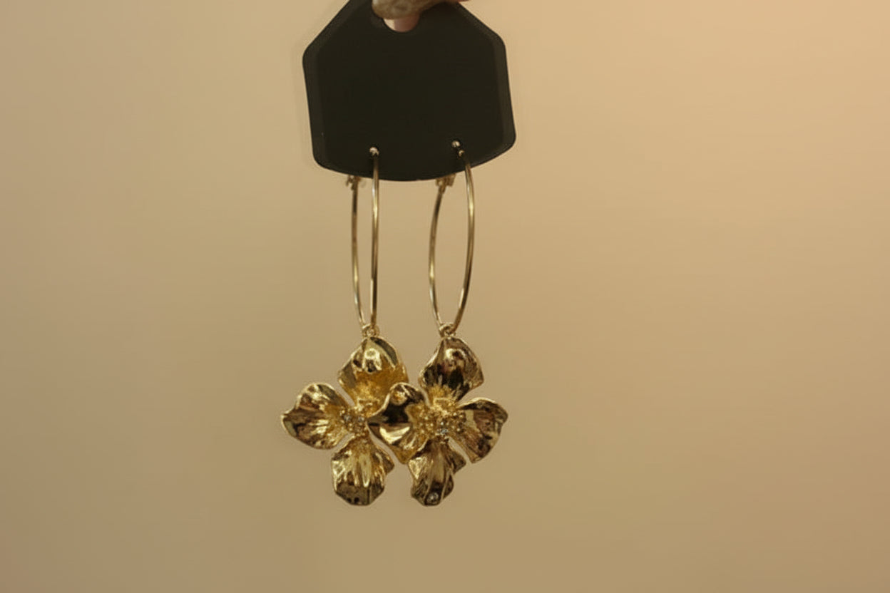 Gold floral earrings on a beige background