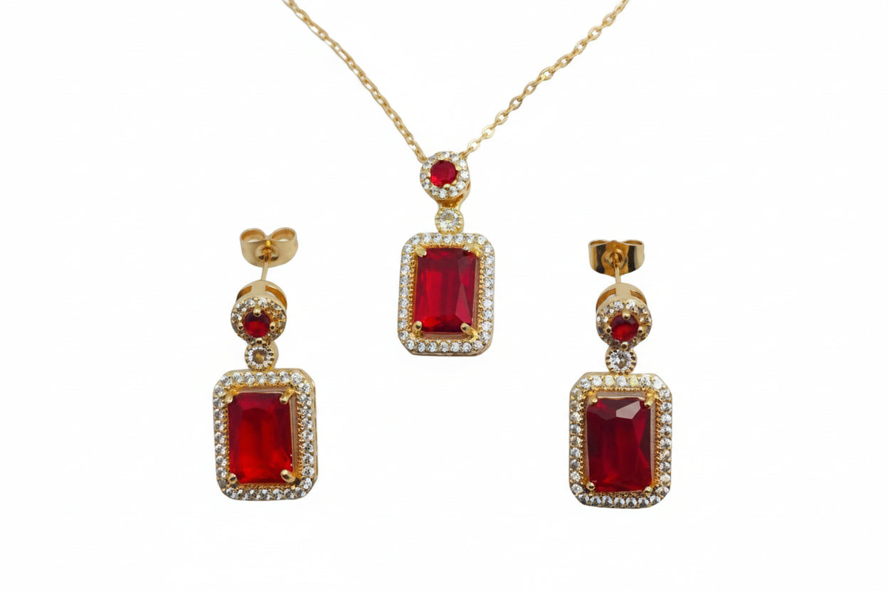 Gold jewelry set with red gemstones on a white background
