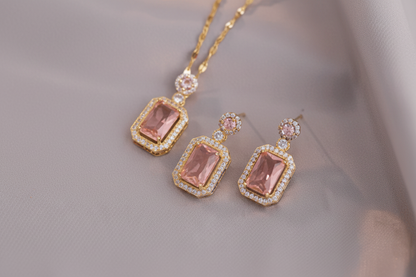 Gold jewelry set with pink gemstones on a neutral background