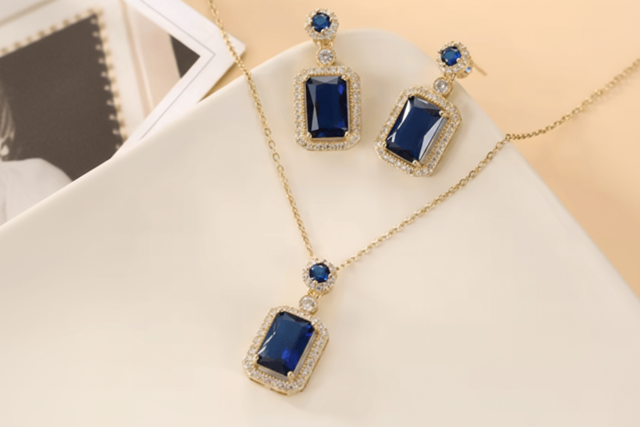 Jewelry set with blue gemstones and gold accents on a light background