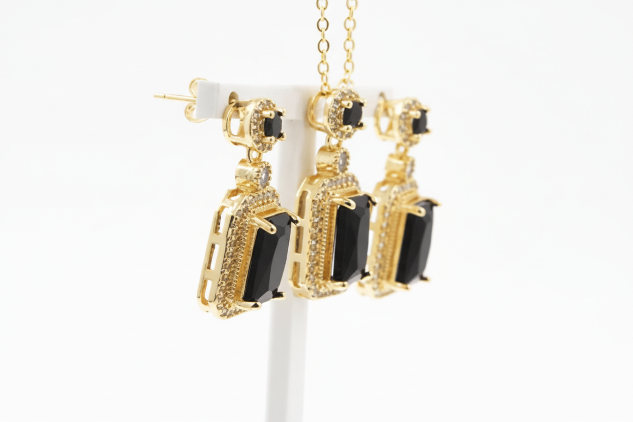 Gold and black earrings on a white stand with a white background