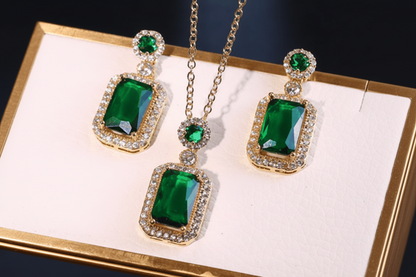 Green gemstone earrings with gold and clear stones on a white background