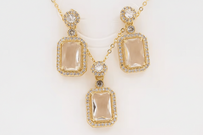 Gold jewelry set with pendant and earrings on a white background