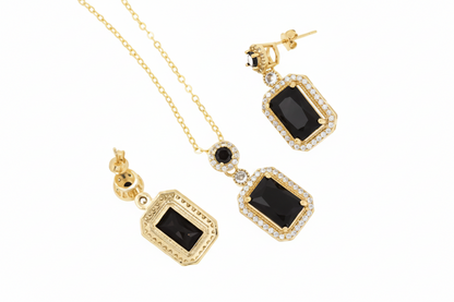 Gold necklace and earrings with black gemstones on a white background