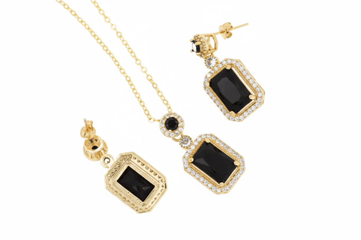Gold necklace and earrings with black gemstones on a white background