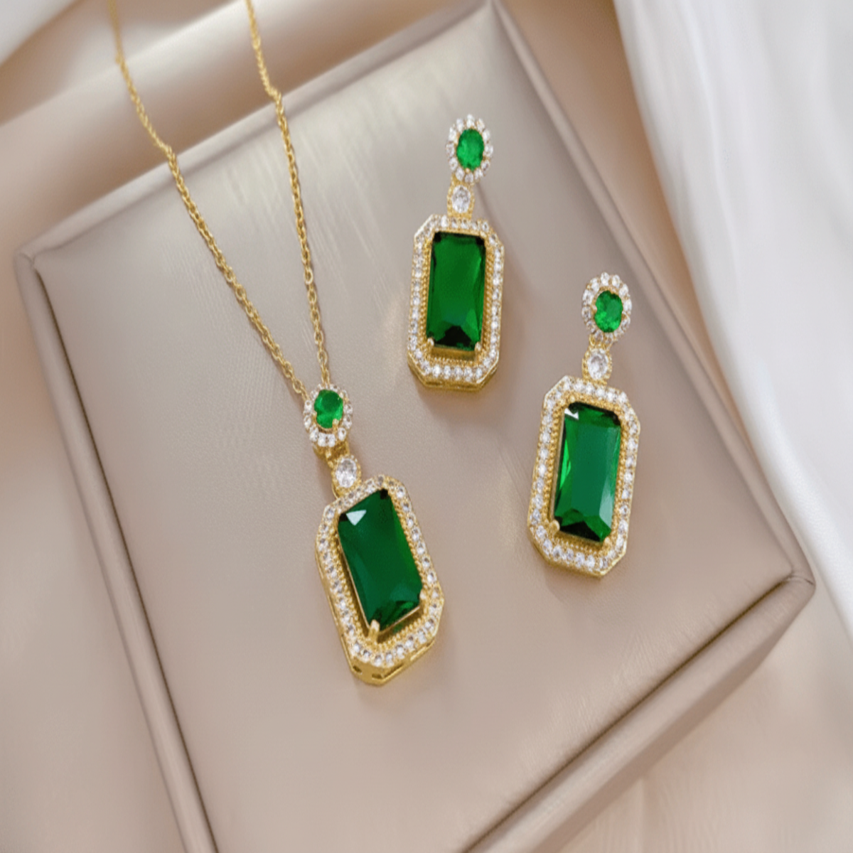 Jewelry set with green gemstones and gold accents on a beige surface