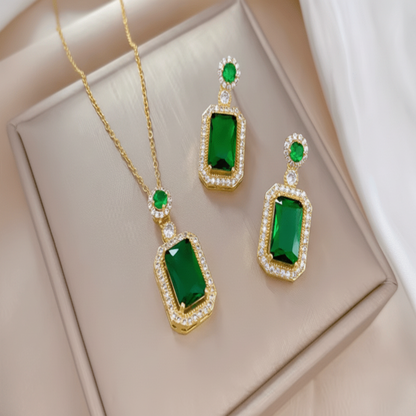 Jewelry set with green gemstones and gold accents on a beige surface