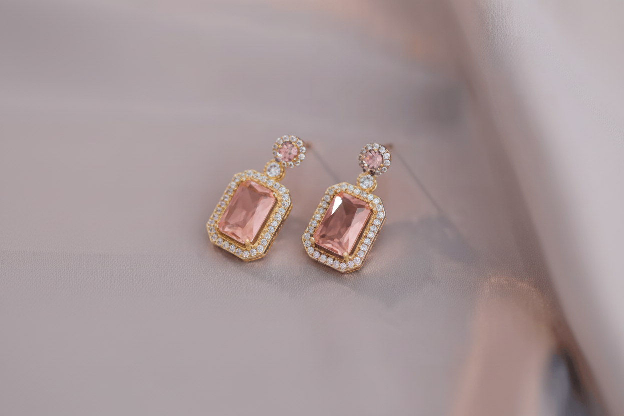 Pair of earrings with pink gemstones on a soft fabric background