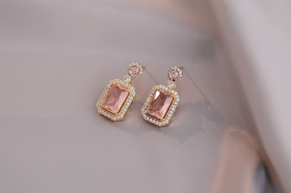 Pair of earrings with pink gemstones on a soft fabric background