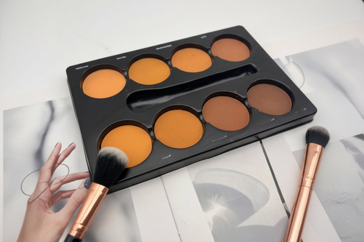 Makeup palette with orange and brown shades and a brush on a light background