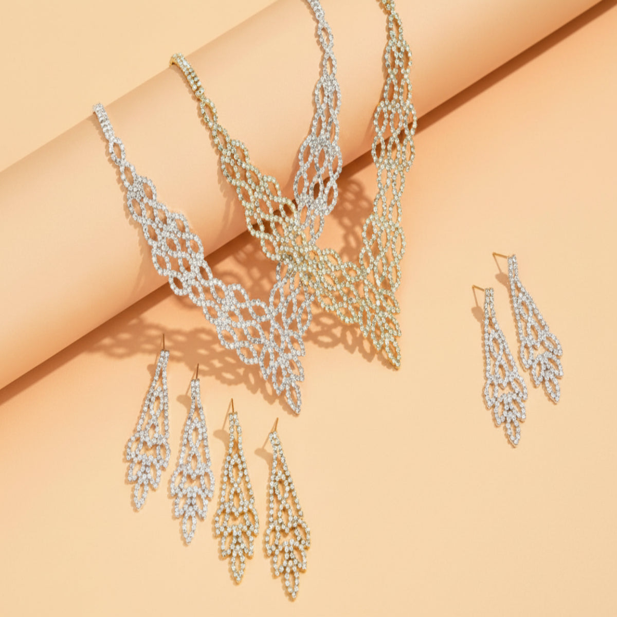 Silver necklace and earrings set on a beige background
