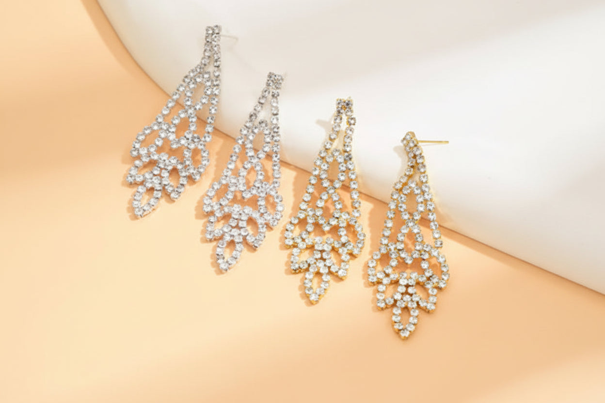 Set of four silver teardrop-shaped earrings on a beige background