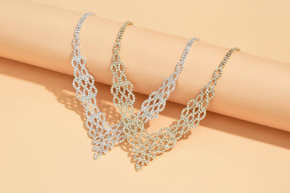 Silver necklace with leaf-like design on a beige surface