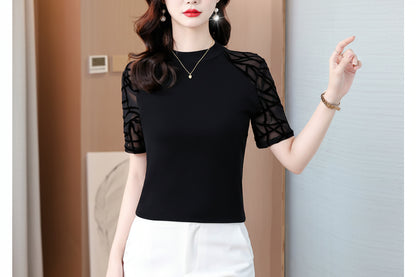 Woman wearing a black top with sheer sleeves against a neutral background