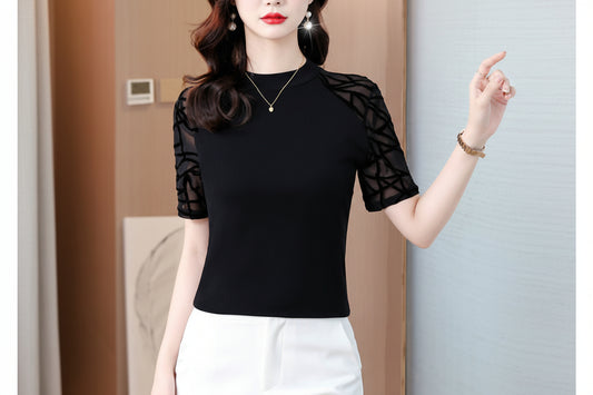 Woman wearing a black top with sheer sleeves against a neutral background