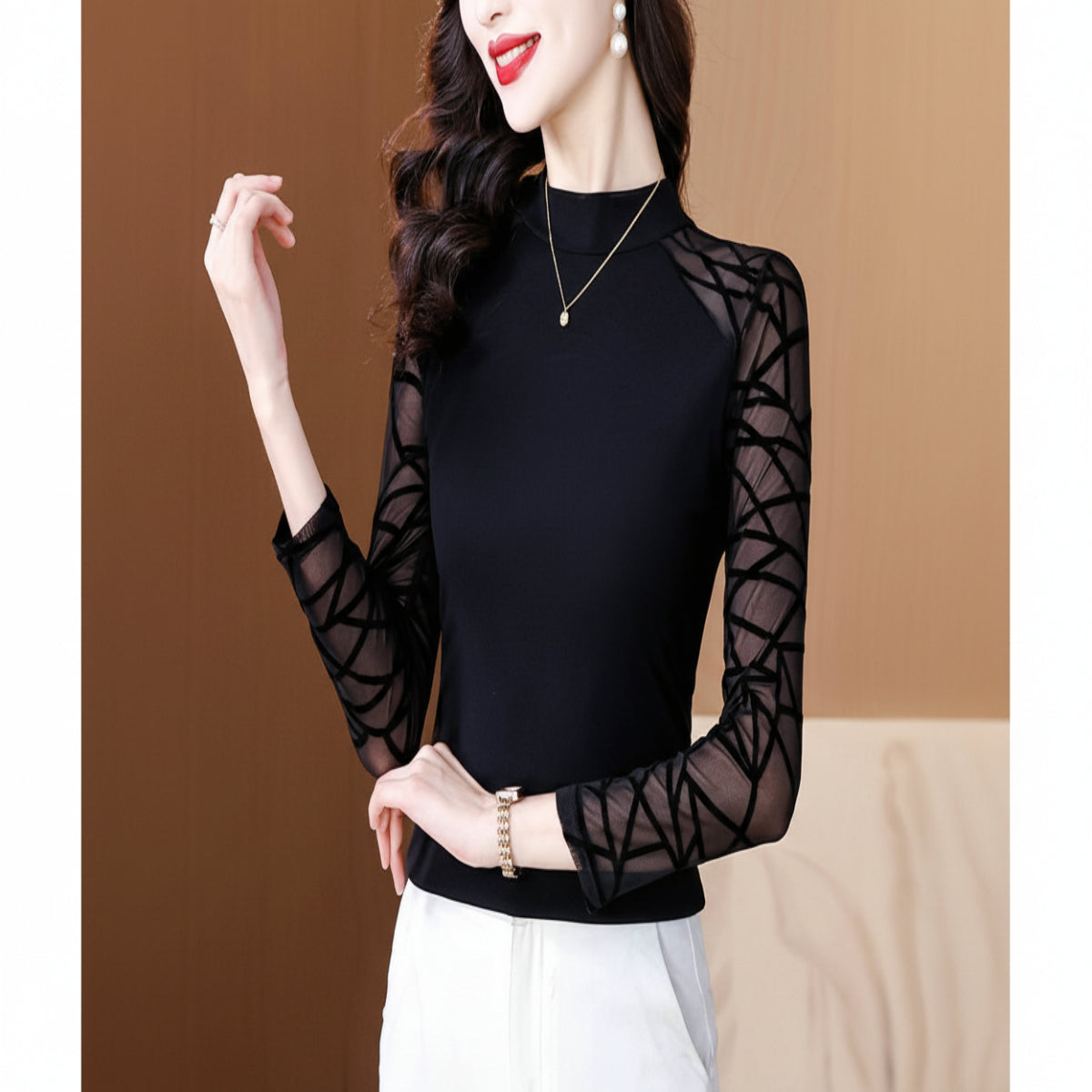 Black long-sleeve top with sheer mesh panels worn by a model against a brown background