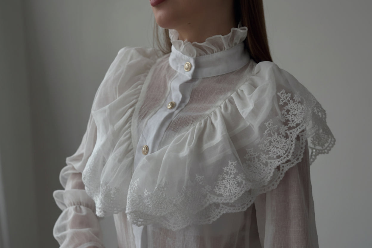 Close-up of a person wearing a white lace blouse with a blurred background