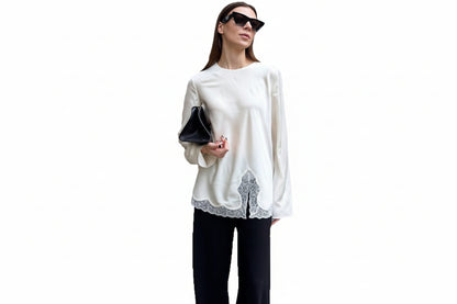 Woman wearing a white blouse with lace details and black pants on a white background