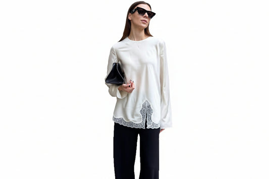 Woman wearing a white blouse with lace details and black pants on a white background