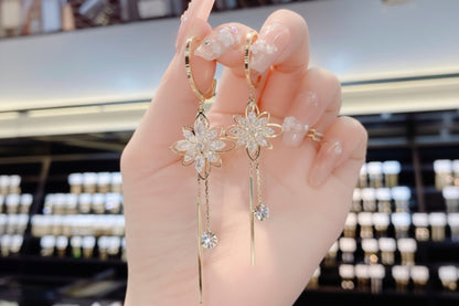 Hand holding a pair of floral earrings with a blurred background