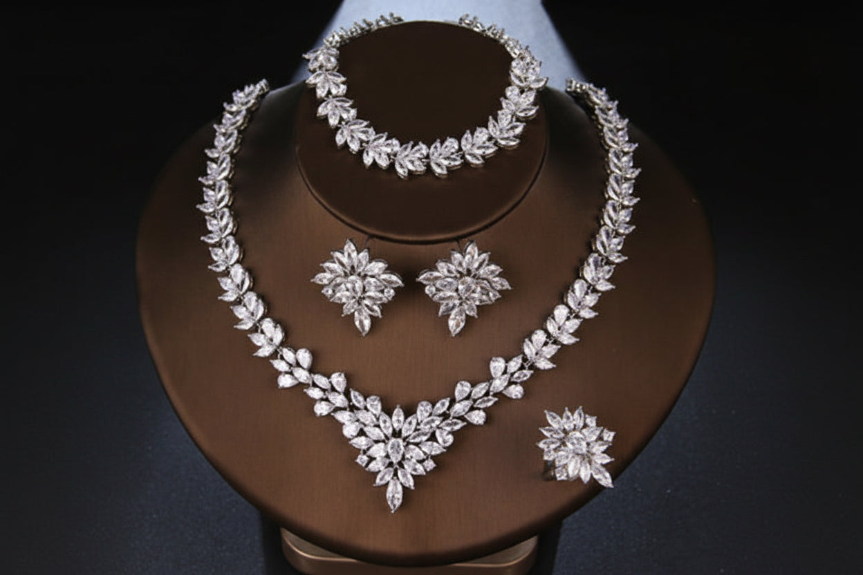 Silver jewelry set including necklace, bracelet, and earrings on a brown stand.